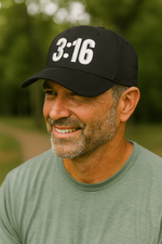 Man wearing a black Christian trucker cap with '3:16' printed on the front panel.