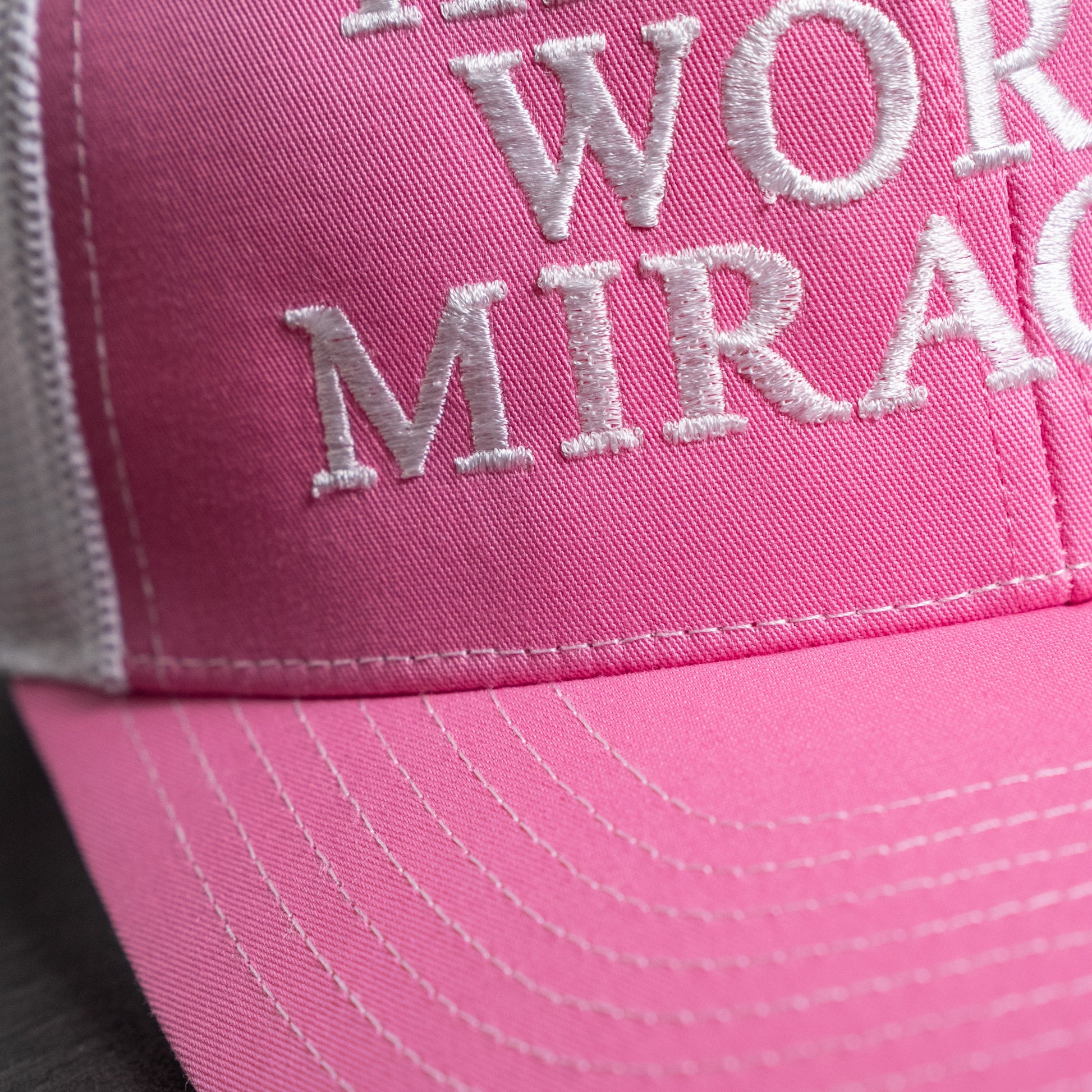 Embroidered faith statement on front of stylish pink and white trucker hat with structured crown  