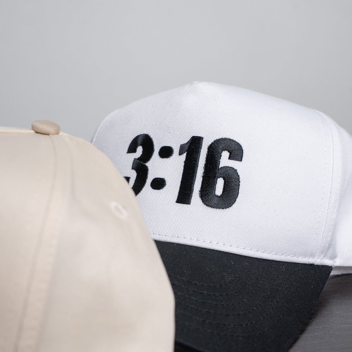 Side angle of breathable five-panel hat in white with embroidered "3:16" detail and fitted closure  