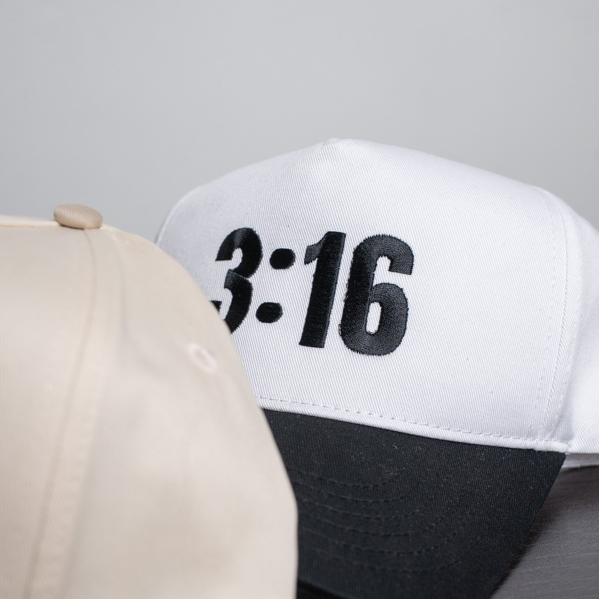 Side angle of breathable five-panel hat in white with embroidered "3:16" detail and fitted closure  