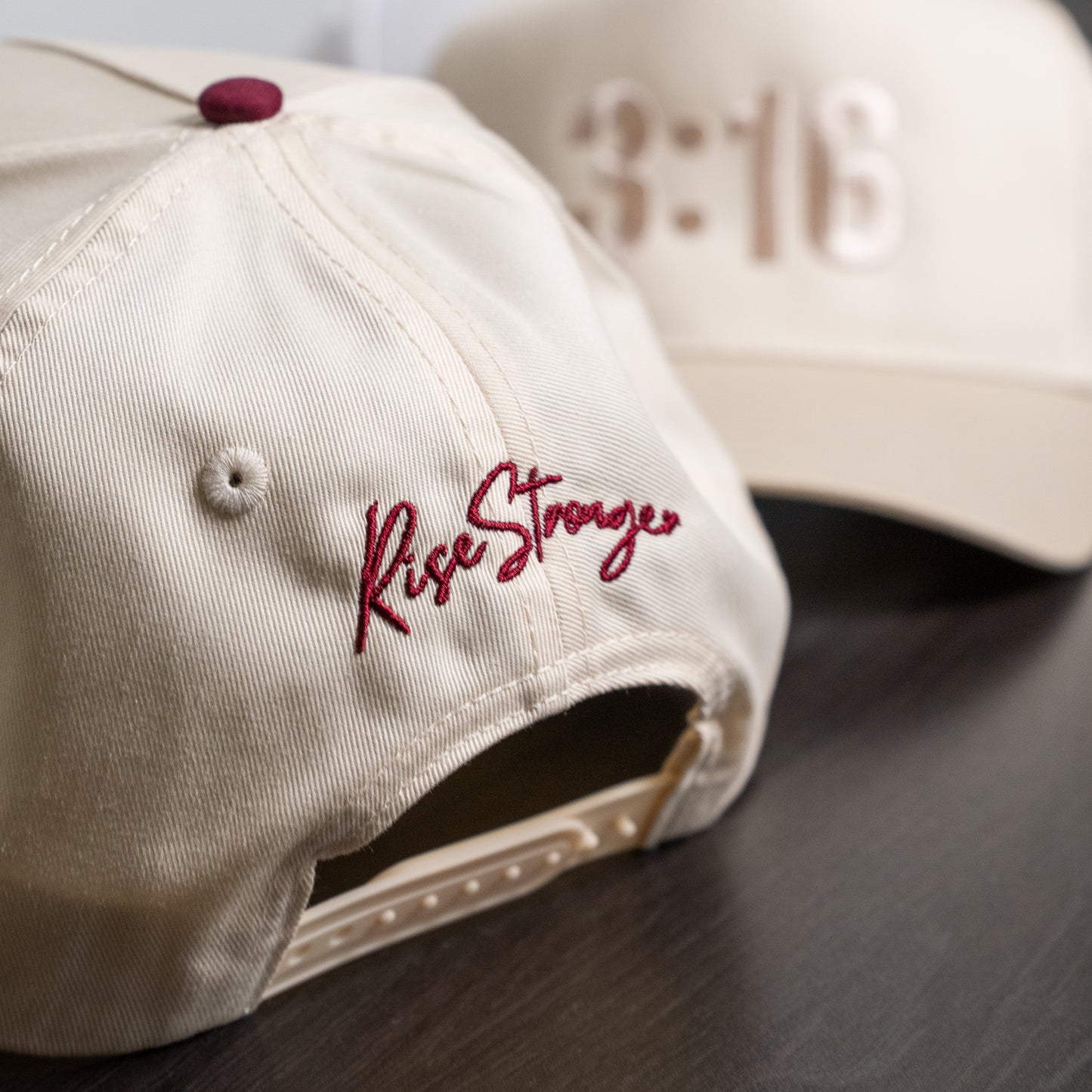 Close-up of embroidered black "3:16" text on structured white cotton twill cap surface  