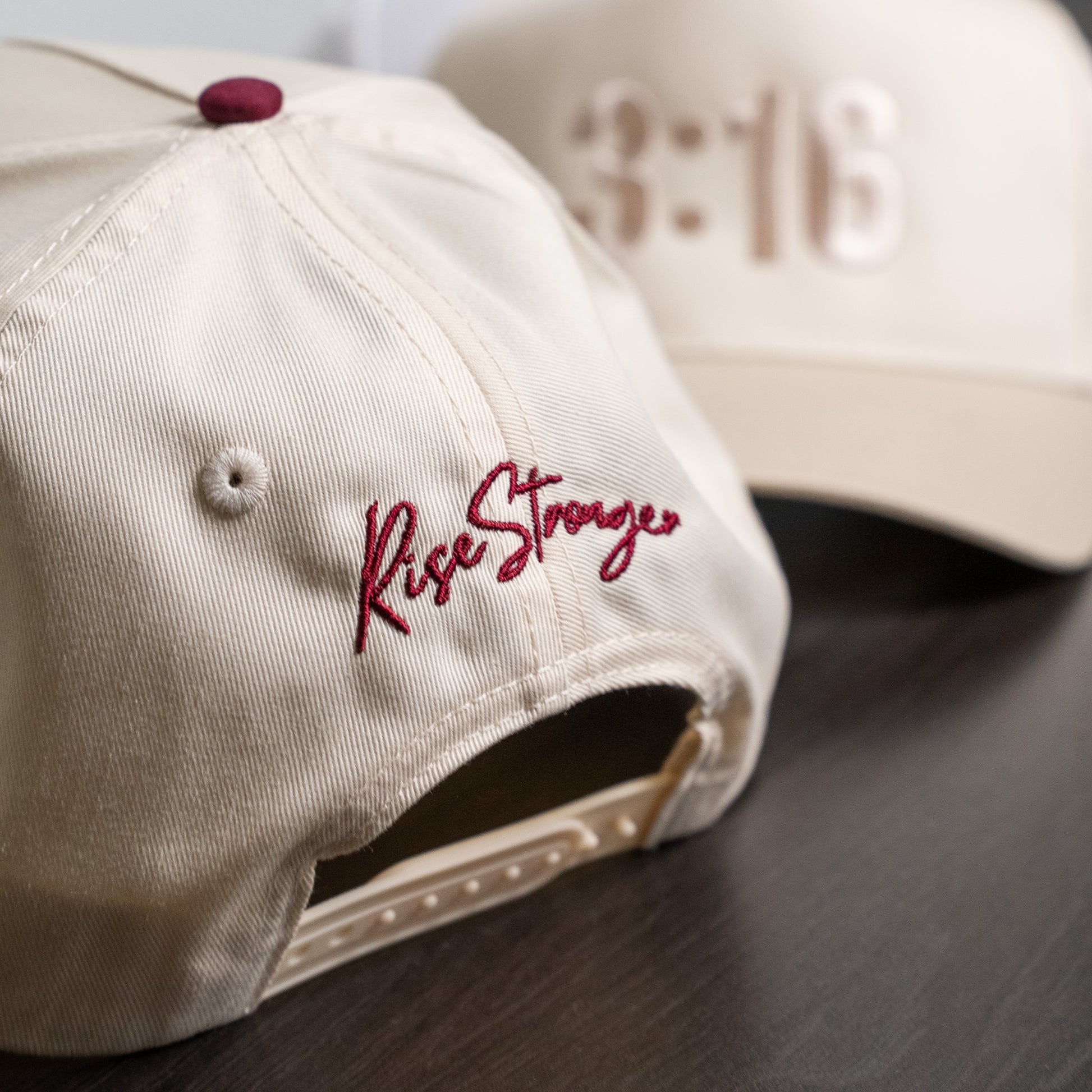 Close-up of embroidered black "3:16" text on structured white cotton twill cap surface  