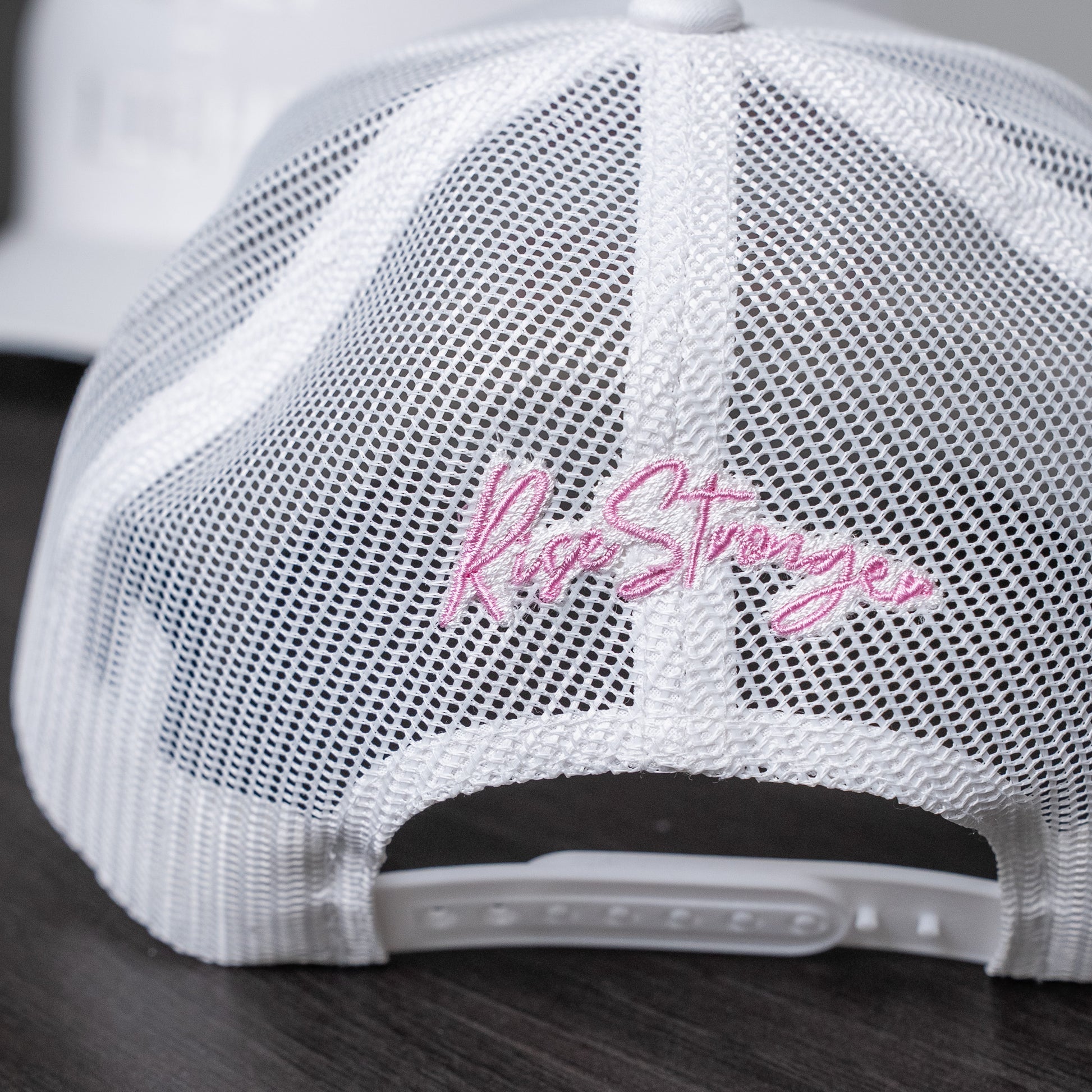 Close-up of pastel yellow embroidered lettering on white trucker cap front panel  