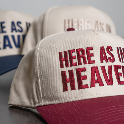 Lifestyle image of a person wearing the “Here As In Heaven” cap outdoors with casual outfit