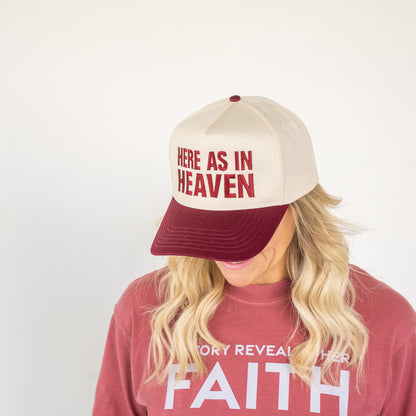 Front view of a two-tone baseball cap with “Here As In Heaven” embroidered in white  
