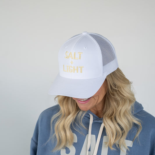 White retro trucker cap with pastel yellow "SALT + LIGHT" embroidery and mesh backing  
