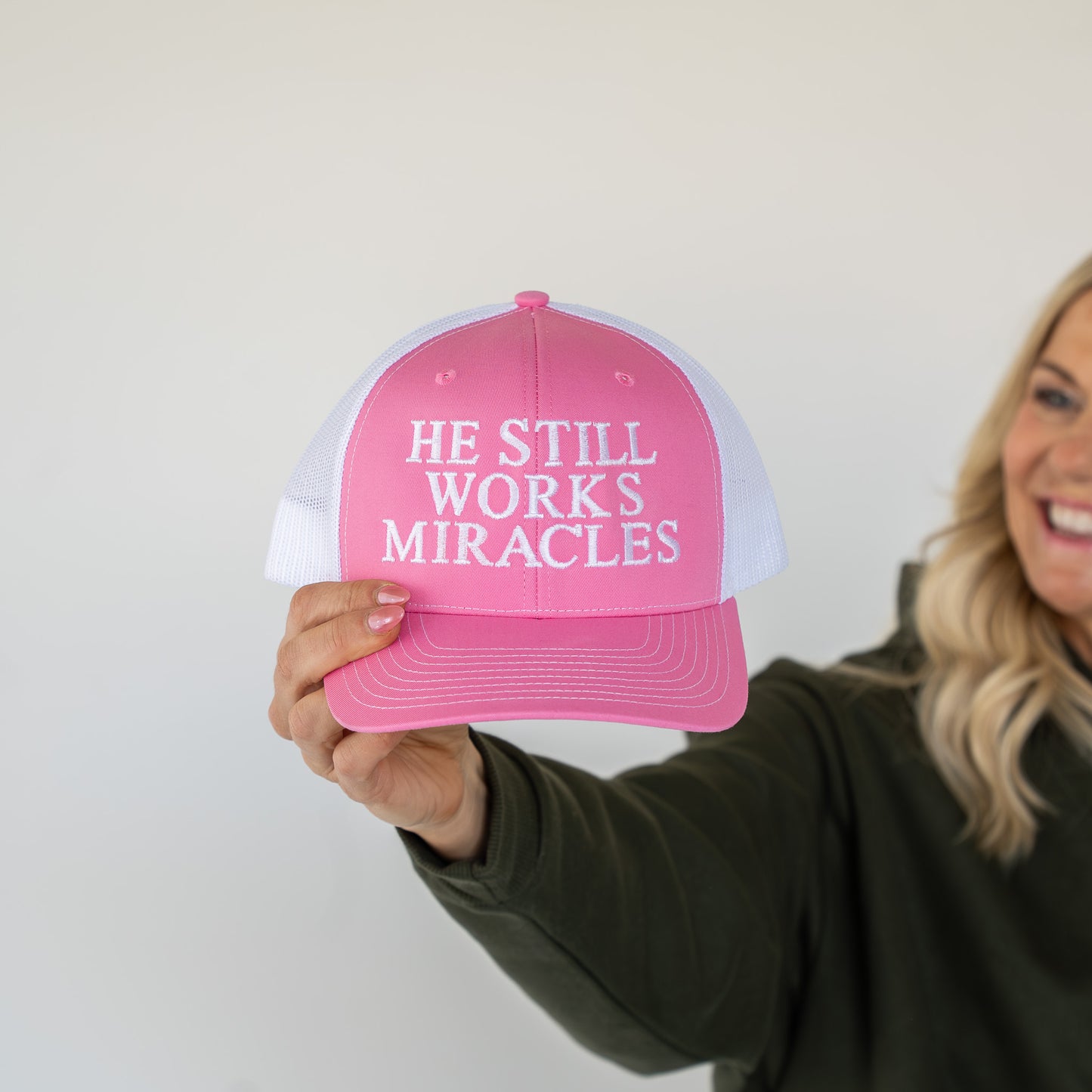 Front view of pink and white adjustable trucker hat highlighting clean embroidery and breathable materials