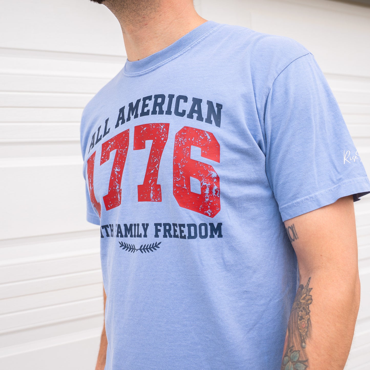 Close-up of red t-shirt sleeve showing Rise Stronger logo