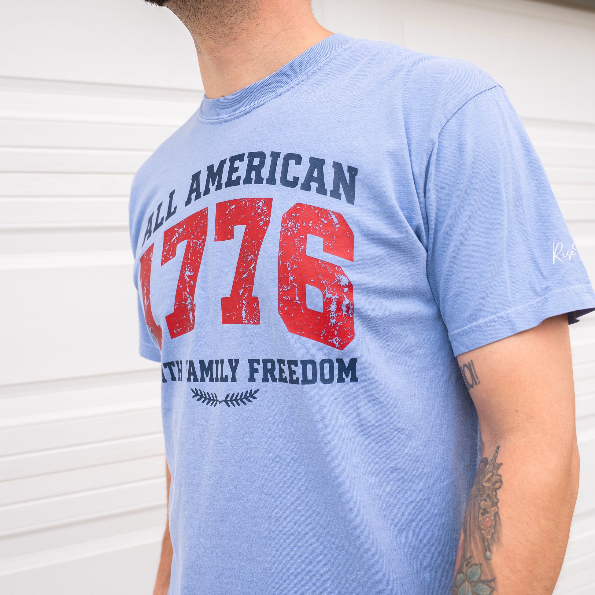 Close-up of red t-shirt sleeve showing Rise Stronger logo