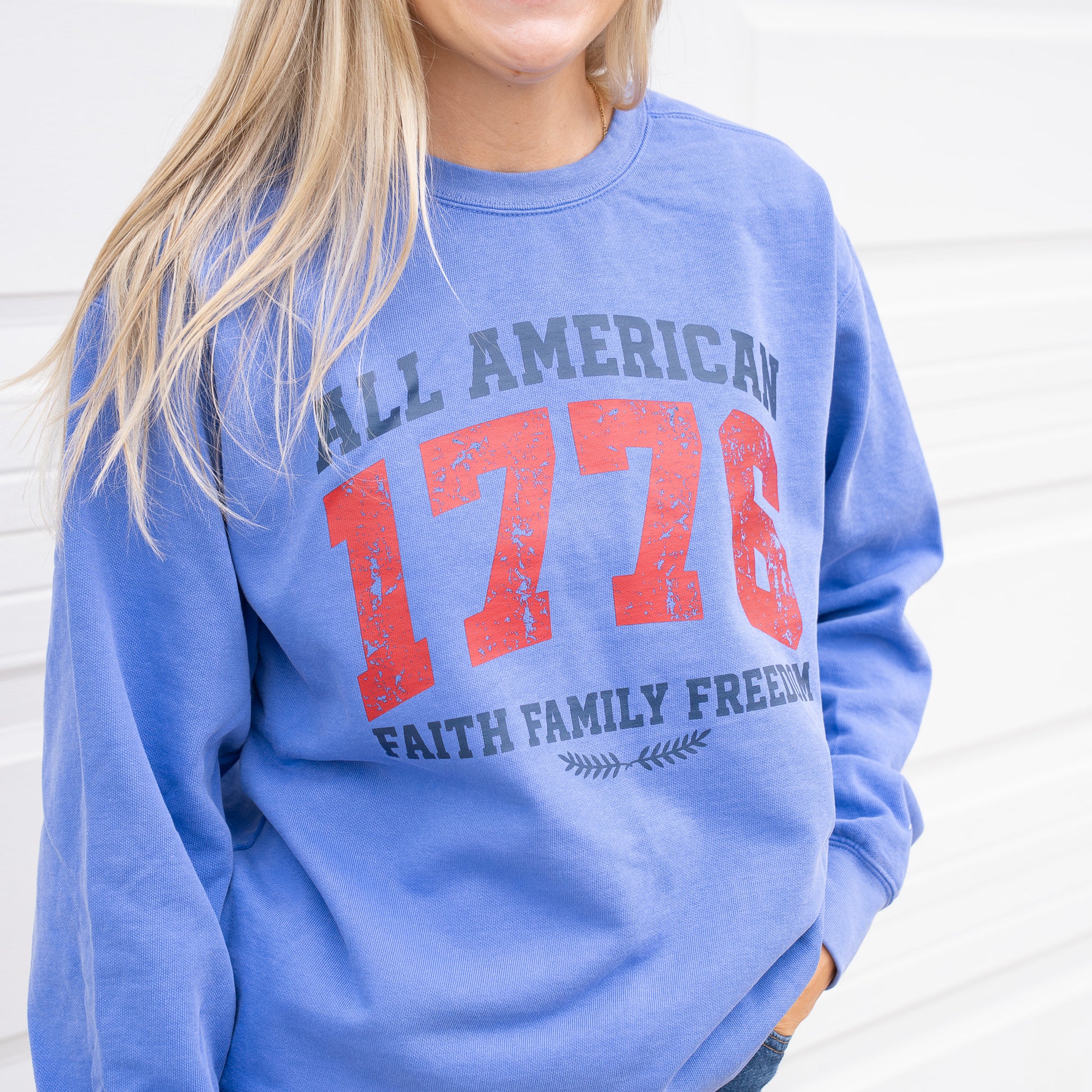 Woman wearing a 1776 All American crewneck sweatshirt in a casual outdoor setting  