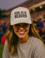 Woman wearing a white Christian trucker cap with 'Here As In Heaven' embroidered on the front