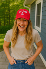 Woman wearing a red cap with 'Holy Spirit & Fire' text, standing outdoors.