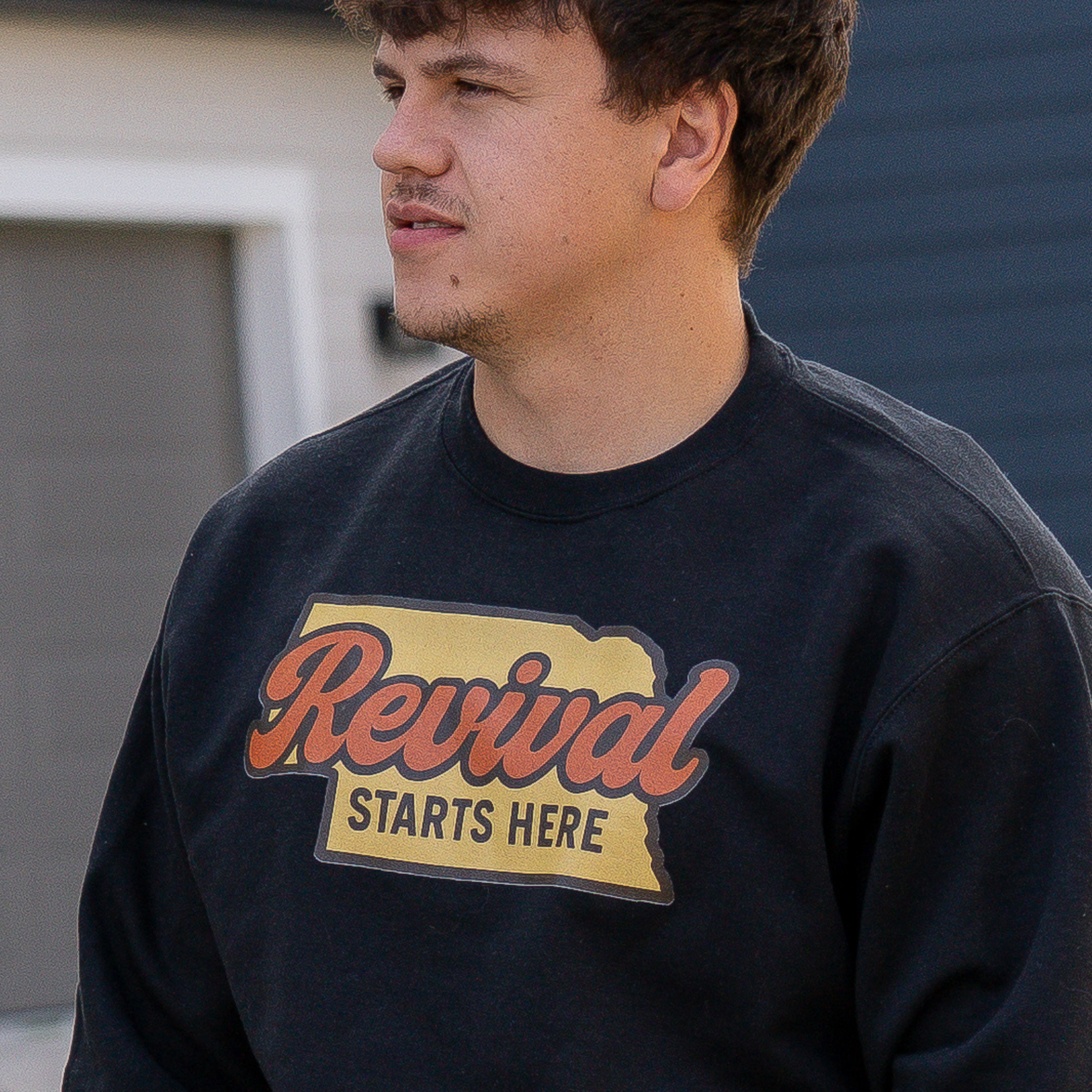 Male wearing a black sweatshirt with 'Revival Starts Here' text