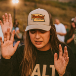 Woman wearing trucker cap with 'Revival Starts Here' overlaying the state of Nebraska. 