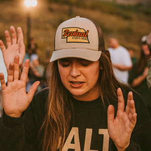 Woman wearing trucker cap with 'Revival Starts Here' overlaying the state of Nebraska. 