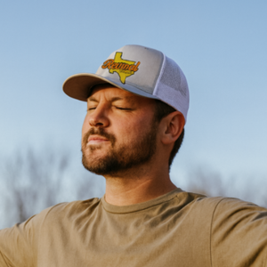 Man worshiping and wearing a grey 'Revival Starts Here' Texas hat.