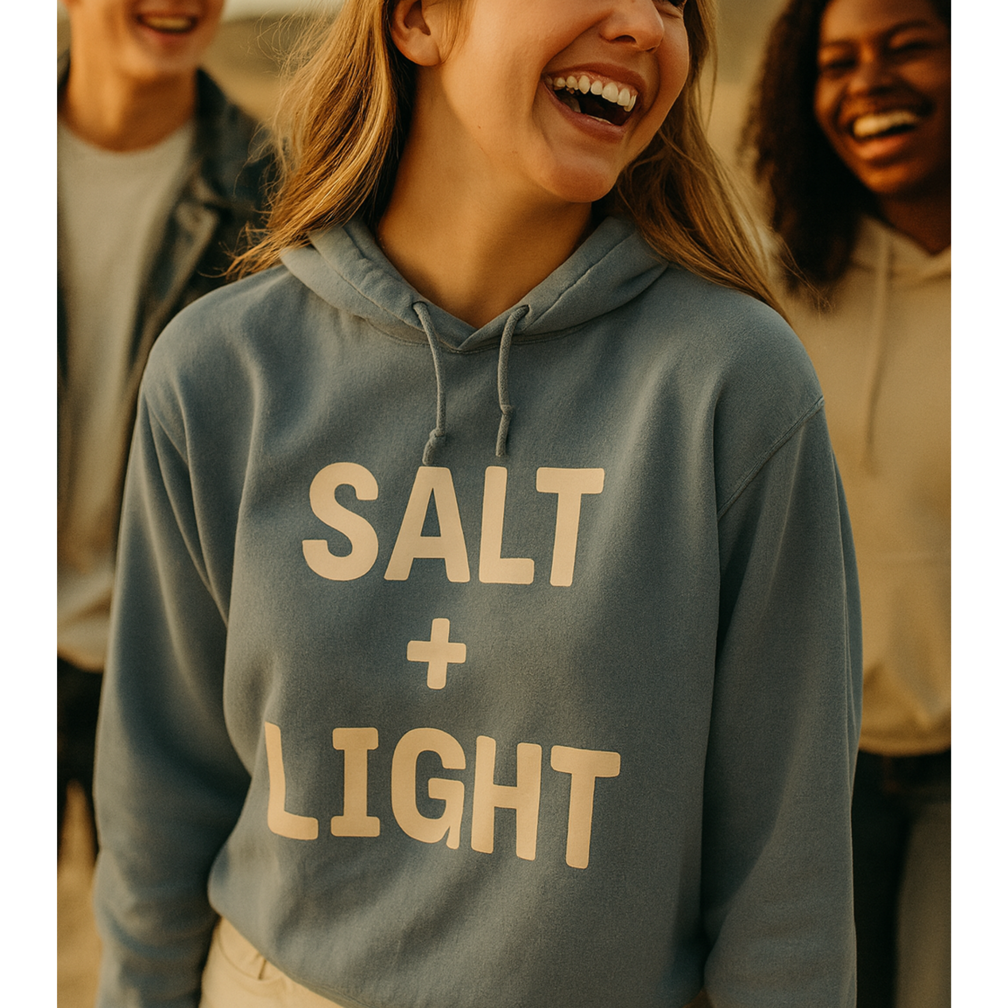 Young Christian woman wearing a 'SALT + LIGHT' hoodie with two friends in the background.