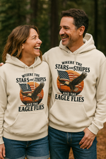Man and women wearing a cream colored Christian & patriotic hoodie with Where the Stars & Stripes and Eagle Flies on the front. 